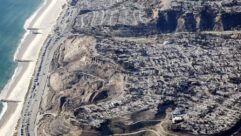 An aerial view of fire trucks, utility, and other vehicles parked along Pacific Coast Highway on January 13, 2025 near homes destroyed in the Palisades Fire as wildfires cause damage and loss through the LA region in Pacific Palisades, California. Multiple wildfires fueled by intense Santa Ana Winds continue to burn across Los Angeles County, with some containment achieved. Photo: Mario Tama/Getty Images.